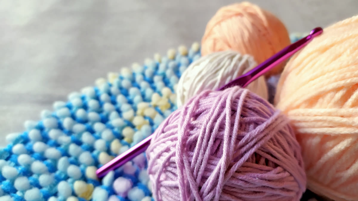 Ovillos de lana de colores con aguja de crochet